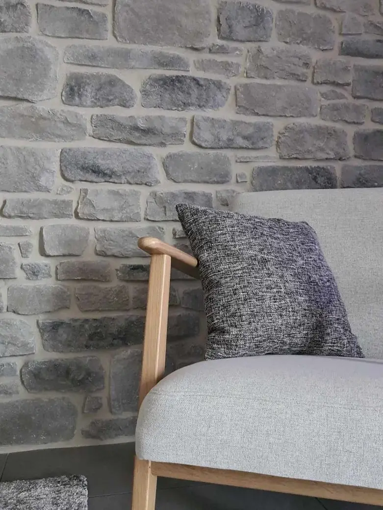Mur intérieur en pierre de parement grise Idéal Grès avec fauteuil moderne