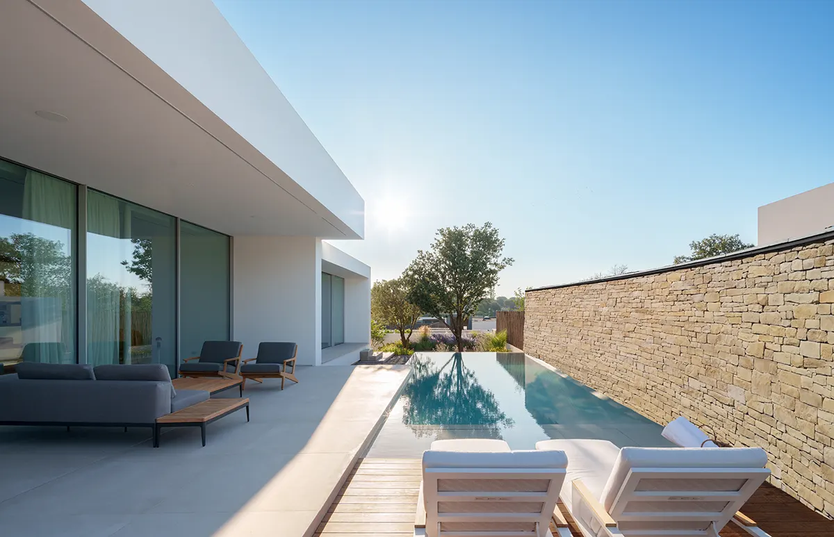 Bords de piscine avec maison en pierre de parement Grès La Rochette
