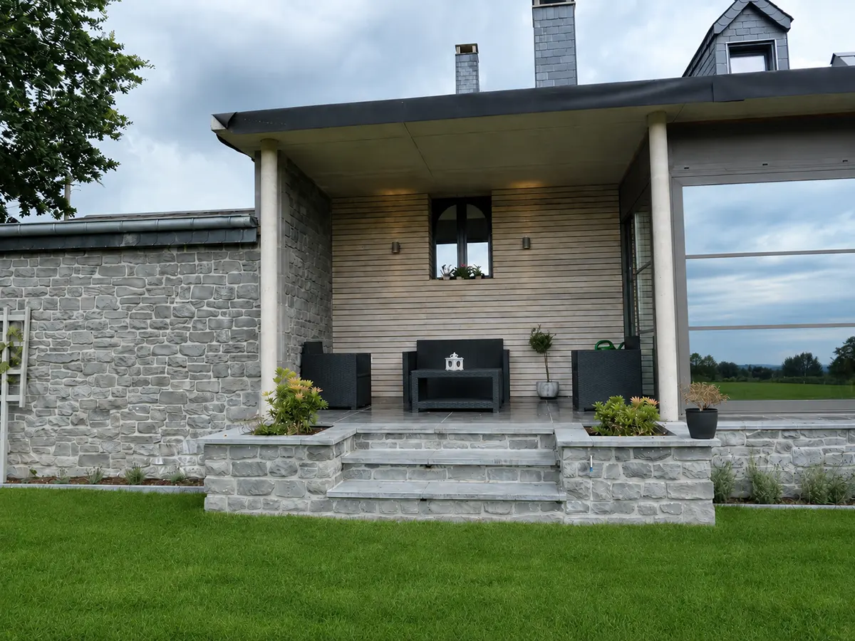 Terrasse extérieure avec murs en pierre, bois et menuiseries contemporaines
